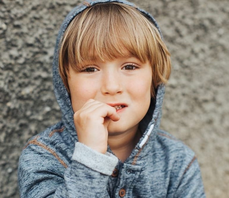 Stressed child biting finger nails, sad toddler boy
